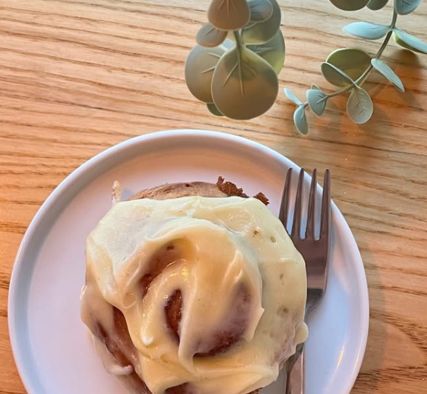 A warm cinnamon bun topped with cream cheese frosting