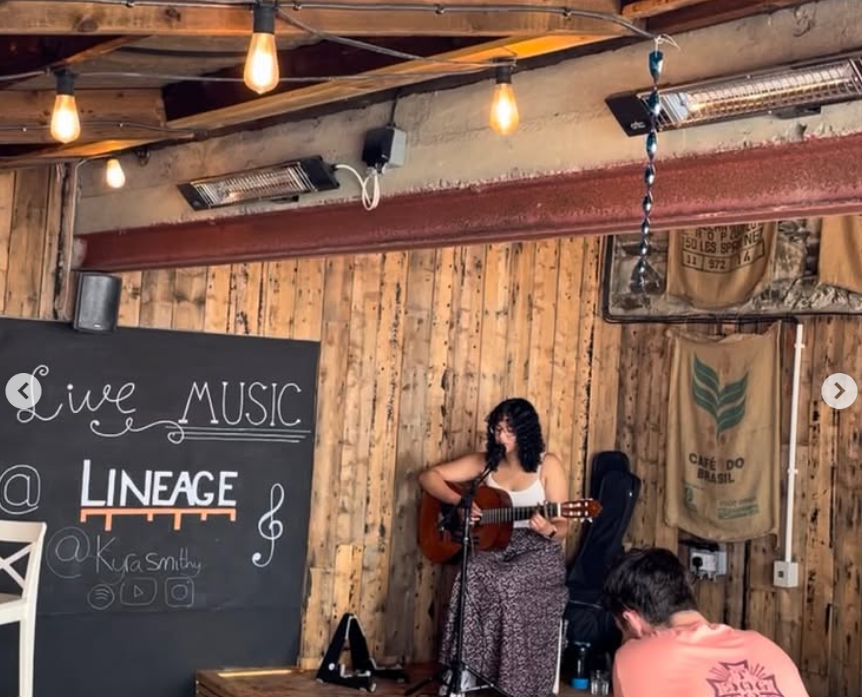 A singer performing live with a guitar in the Lineage courtyard